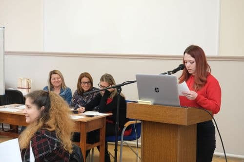 Cseh nap, tanuló olvas fel a zsűri mellett, egy laptop előtt állva egy papírból