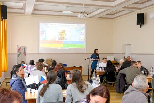 Cseh nap, Kahoot kvízversen, háttérben a kivetítőn a kérdések, előtérben asztaloknálk a verszenyzők