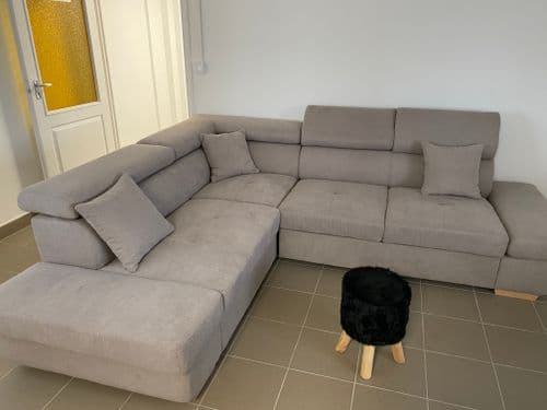 Textil sarokgarnitúra párnákkal, előtte kisszék