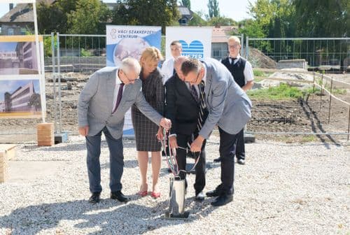 Dudás Tibor Kancellár és az államtitkárok éppen leeresztik a fényes fémhengert a lyukba (időkapszula)